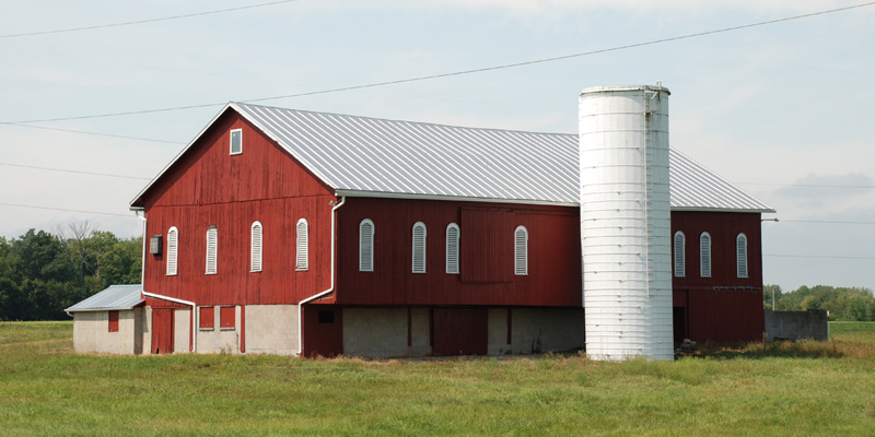 Red farm building located in field.