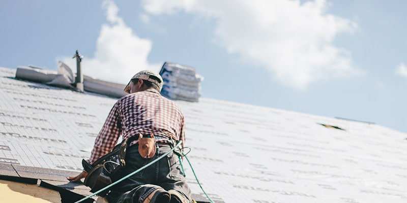 Roofer adding shingles to house