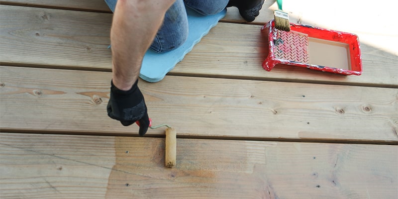 man painting wooden decking