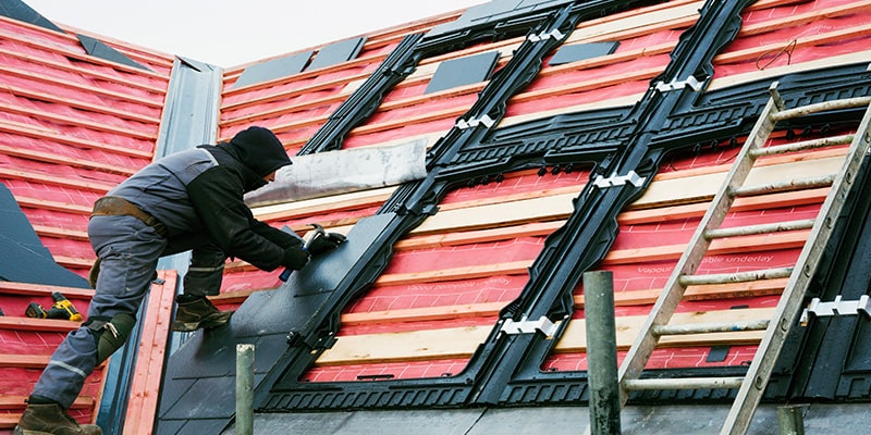 Roofer replacing tiles at house