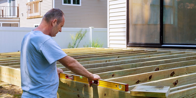 man measuring wooden patio