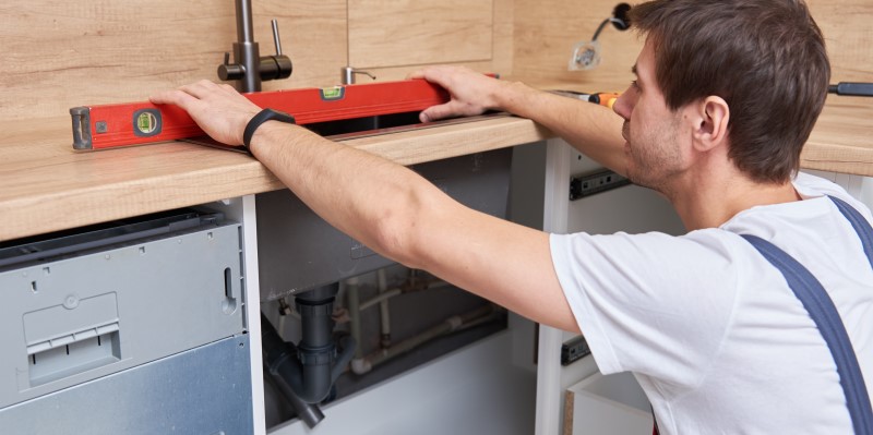 plumber installing sink in kitchen