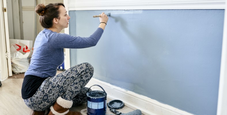 woman painting wall in home